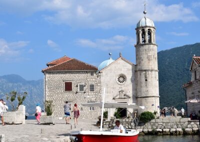 A photo of a red boat moored to Our Lady of the Rocks in Montenegro