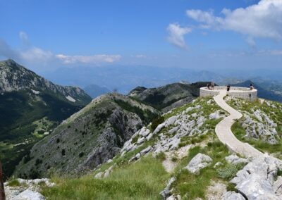 Photo of Mount Lovćen with a path along the ridge of a mountain with blue sky in the distance