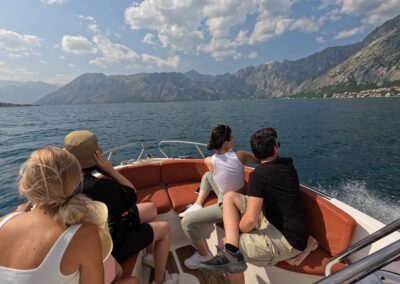 Speed boat with volunteers sitting inside as it travels towards Our Lady of the Rocks in Kotor bay, Montenegro