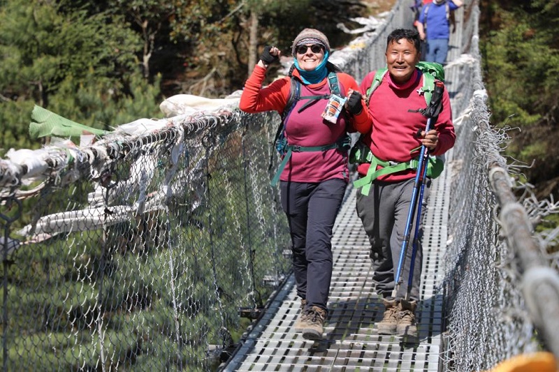 Judy crossing a bridge over a valley on the Everest Base Camp trek
