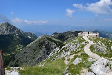 Photo of Mount Lovćen with a path along the ridge of a mountain with blue sky in the distance