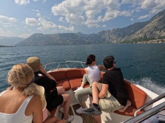 Speed boat with volunteers sitting inside as it travels towards Our Lady of the Rocks in Kotor bay, Montenegro