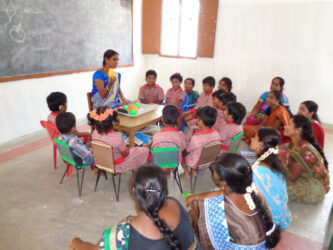 Indian teacher sitting with a class of deaf students at a Deaf school in south India