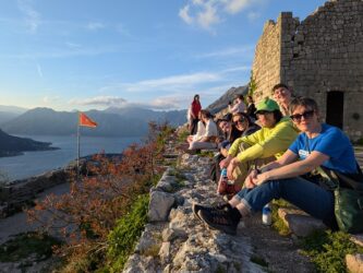 Video showing a group of people sitting on the ground at Kotor castle looking at the view over Kotor in Montenegro